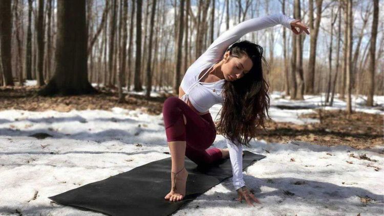 woman doing yoga with woods and snow in the background