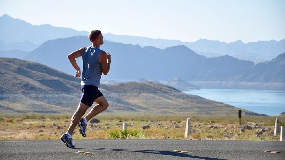 athlete running on a highway with landscape in the background