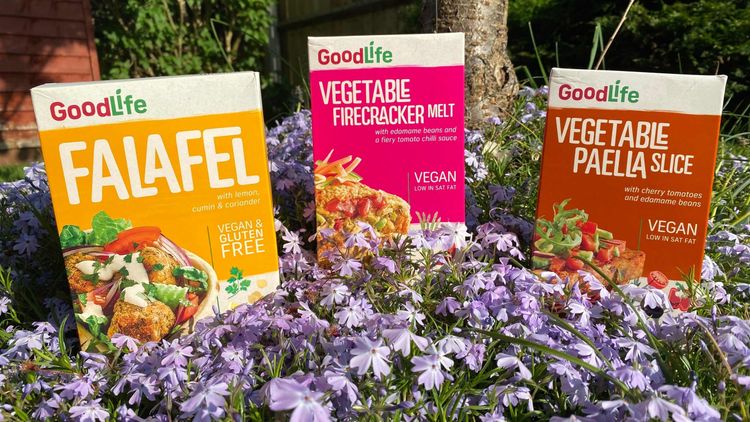 yellow, pink and brown packs of veg food with lavender flowers and open area in the background