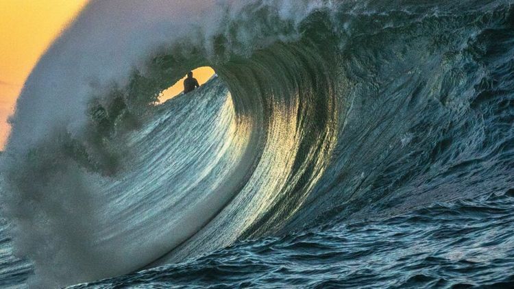 Cresting wave through which a surfer can be seen