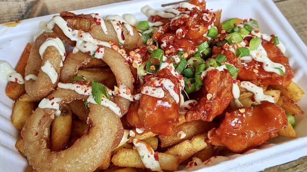 platter of vegan rings and chips with white and red sauce and green coloured topping