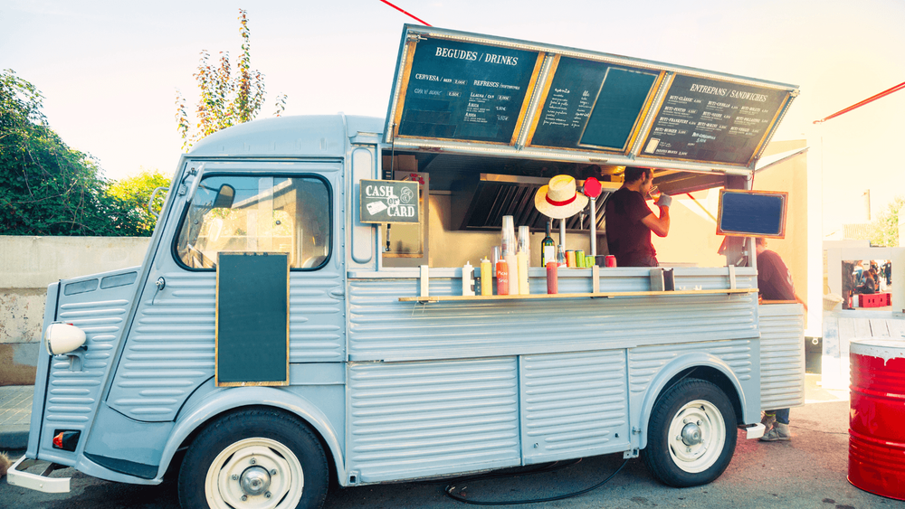 Blue food truck on the pavement next to the sea