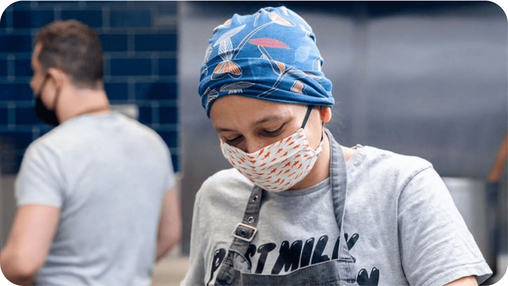 woman in facemask cooking food in a kitchen