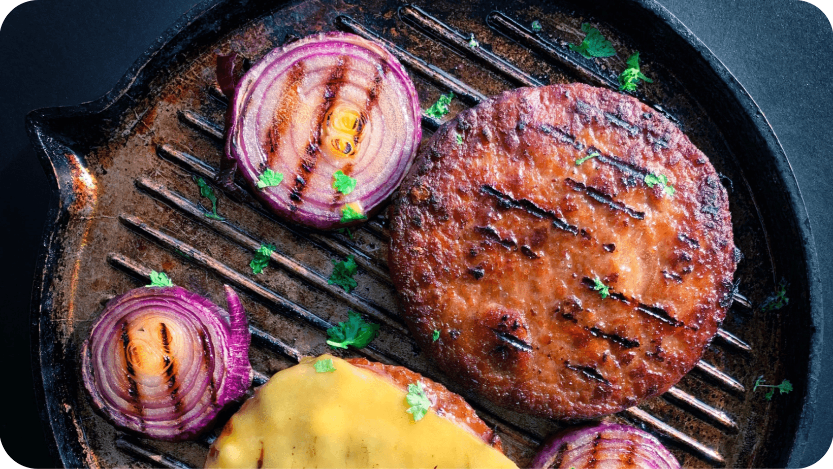 plant-based burger on a skillet pan with red onion and vegan cheese