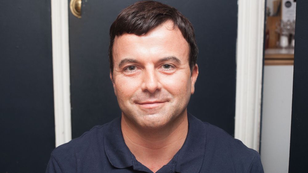 Aaron Calder smiling (a man sitting down in a café)