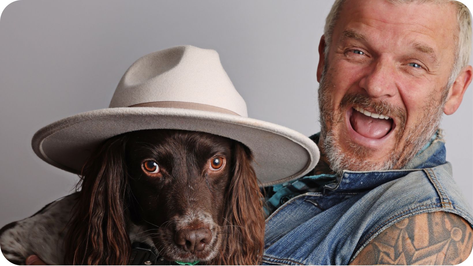 Ecstatic man (Dirty Vegan chef Matt Pritchard) holding his dog which has a hat on