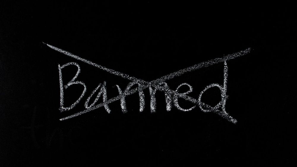 The word ‘banned’ written in white chalk banned crossed out on a blackboard