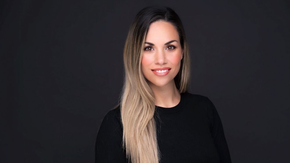 Michaela Pontiki wearing black and smiling in front of a black background 