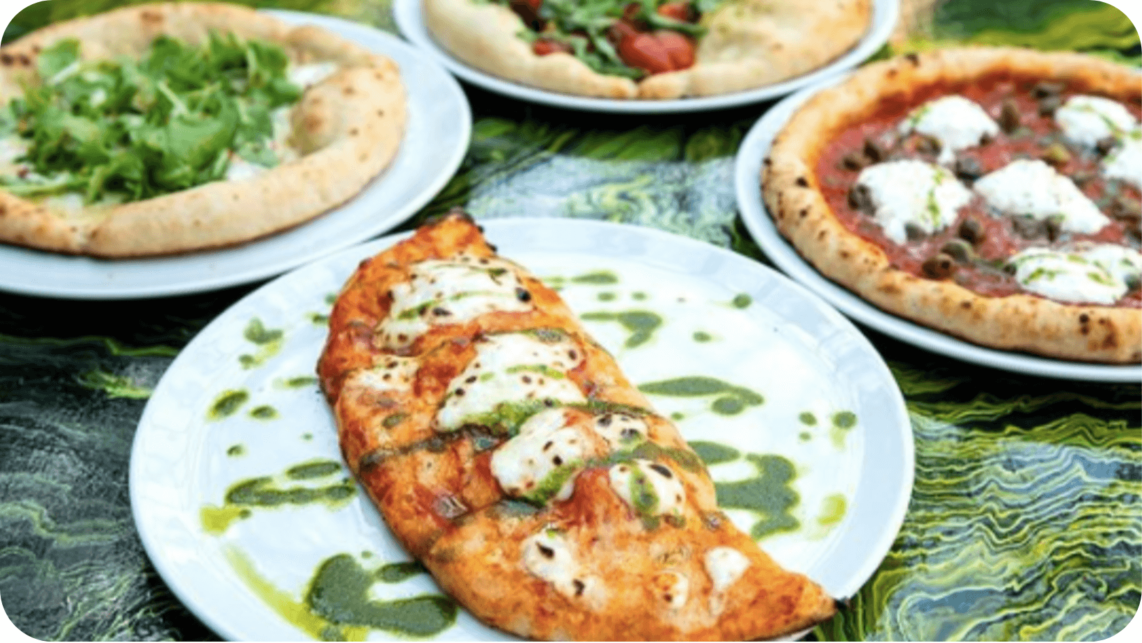 Variety of colourful vegan pizzas and flatbreads on white plates served in the Plant Club restaurant In Hackney