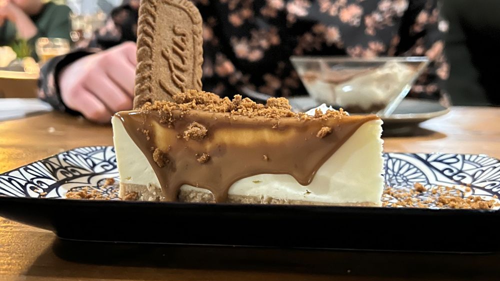 Vegano Newcastle’s Vegan Biscoff cheesecake on a patterned dish with a man next to his vegan tiramisu in the background 