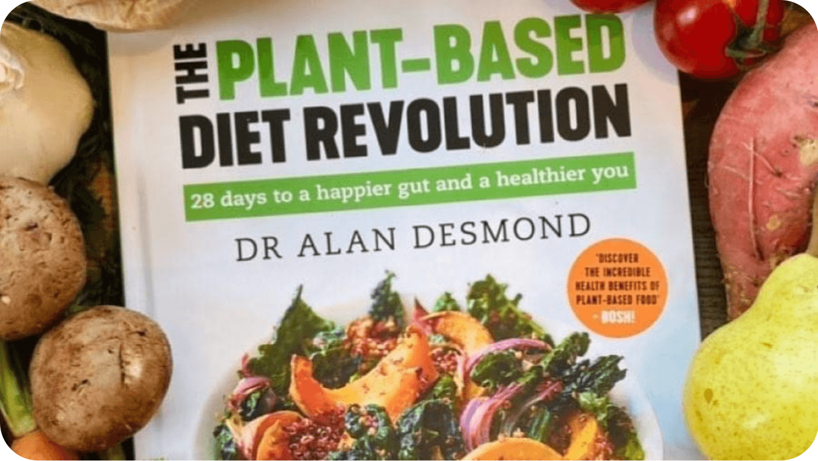 Dr Alan Desmond’s book - The Plant-Based Diet Revolution: 28 days to a happier gut and a healthier you - surrounded by fruit and vegetables 