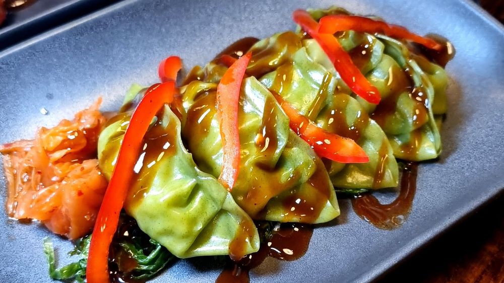 Metropole Bar Brighton’s Green Gyoza with teriyaki sauce on top served on a blue plate