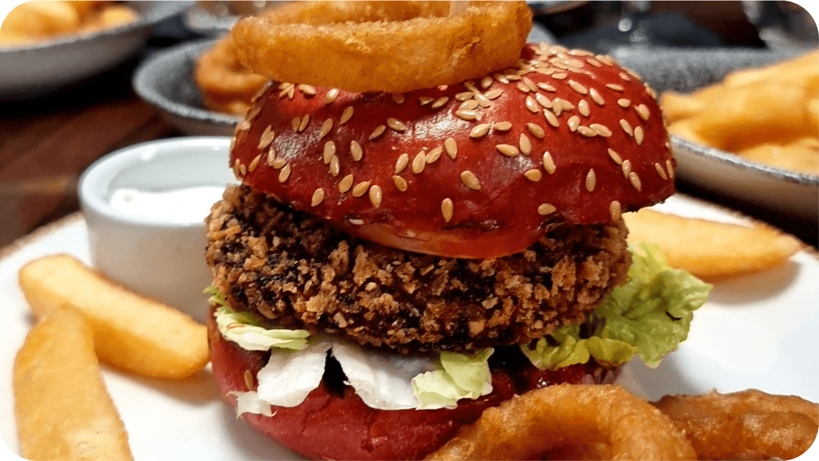  Metropole Bar Brighton’s vegan Plant Burger with linseed bun, chips, onion rings and mayo on a white plate