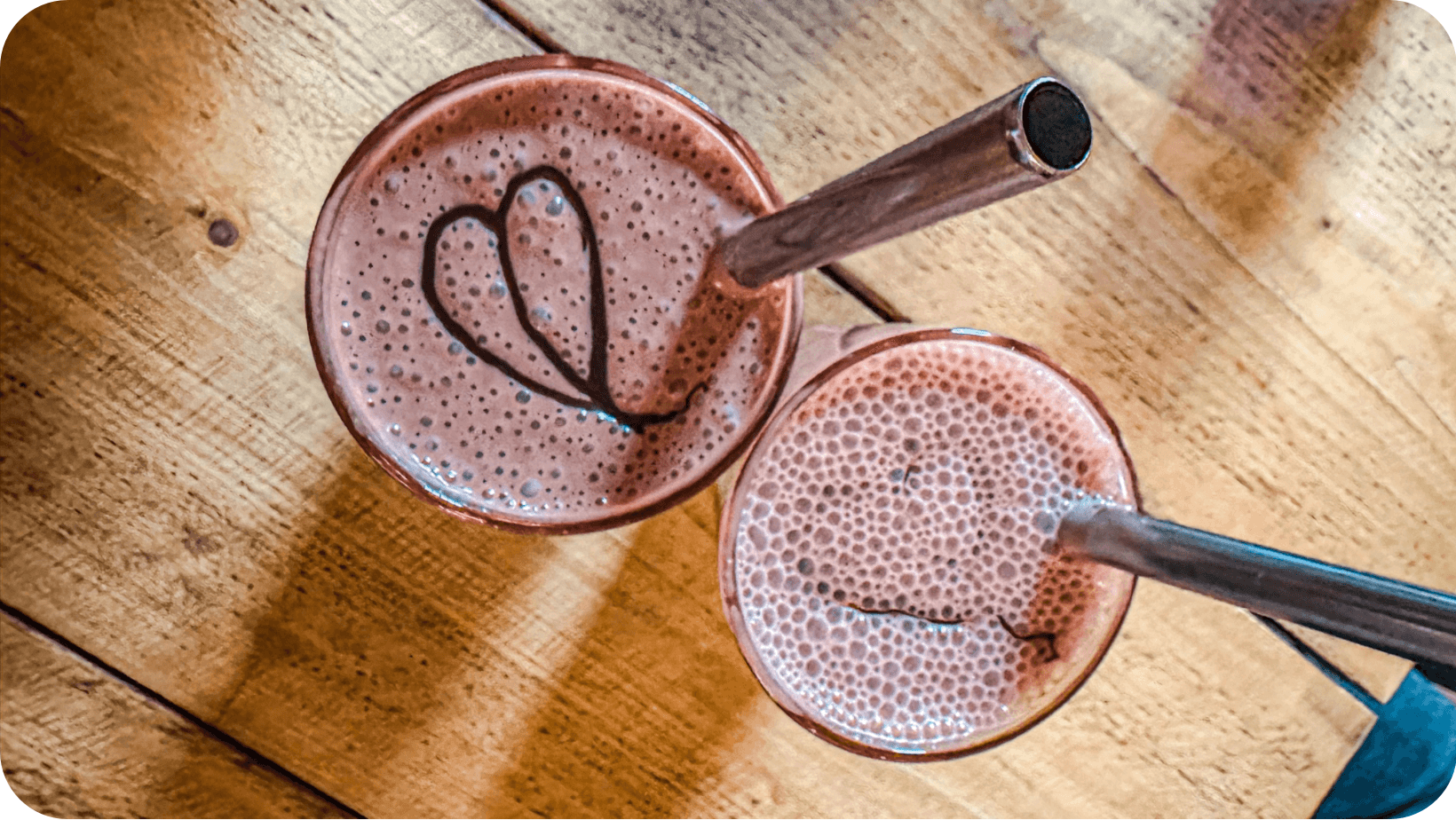 Vegan chocolate smoothies in glasses with metal straws on a wooden table at Seeds For The Soul Edinburgh