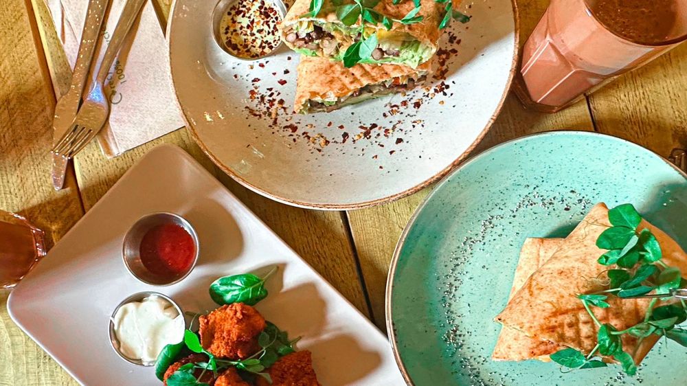 Spread of colourful vegan food and chocolate smoothies on a wooden table in Seeds For The Soul Edinburgh