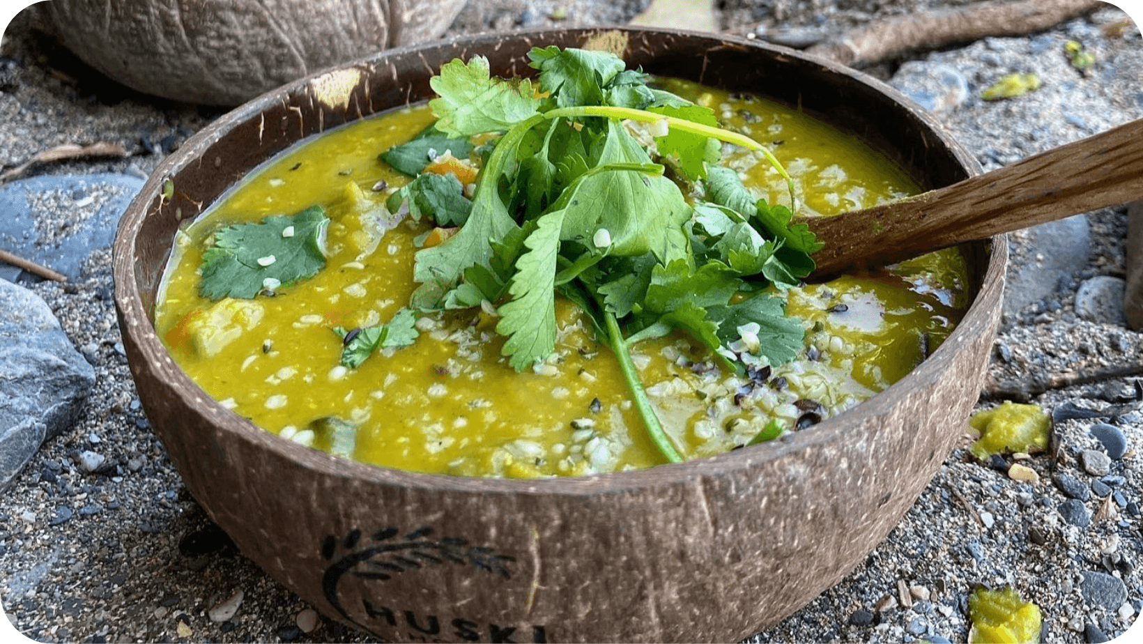 Vegan soup in a brown wooden bowl on a sandy beach