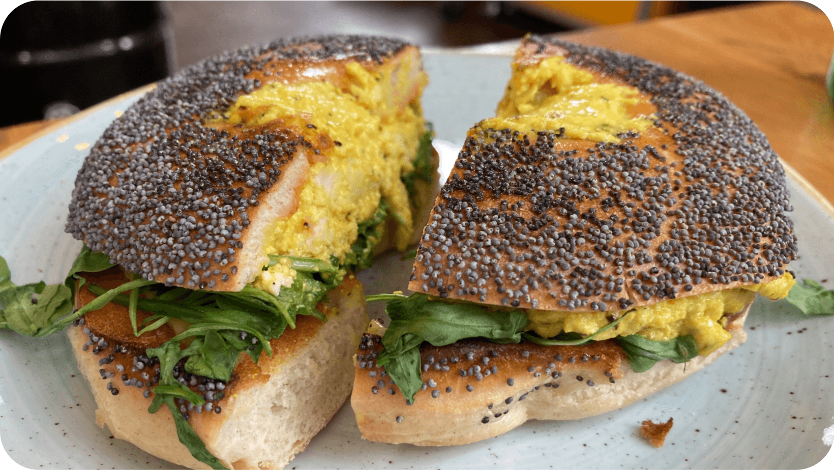 Sliced vegan ‘egg’ bagel with rocket topped with poppy seeds from The Fields Beneath 