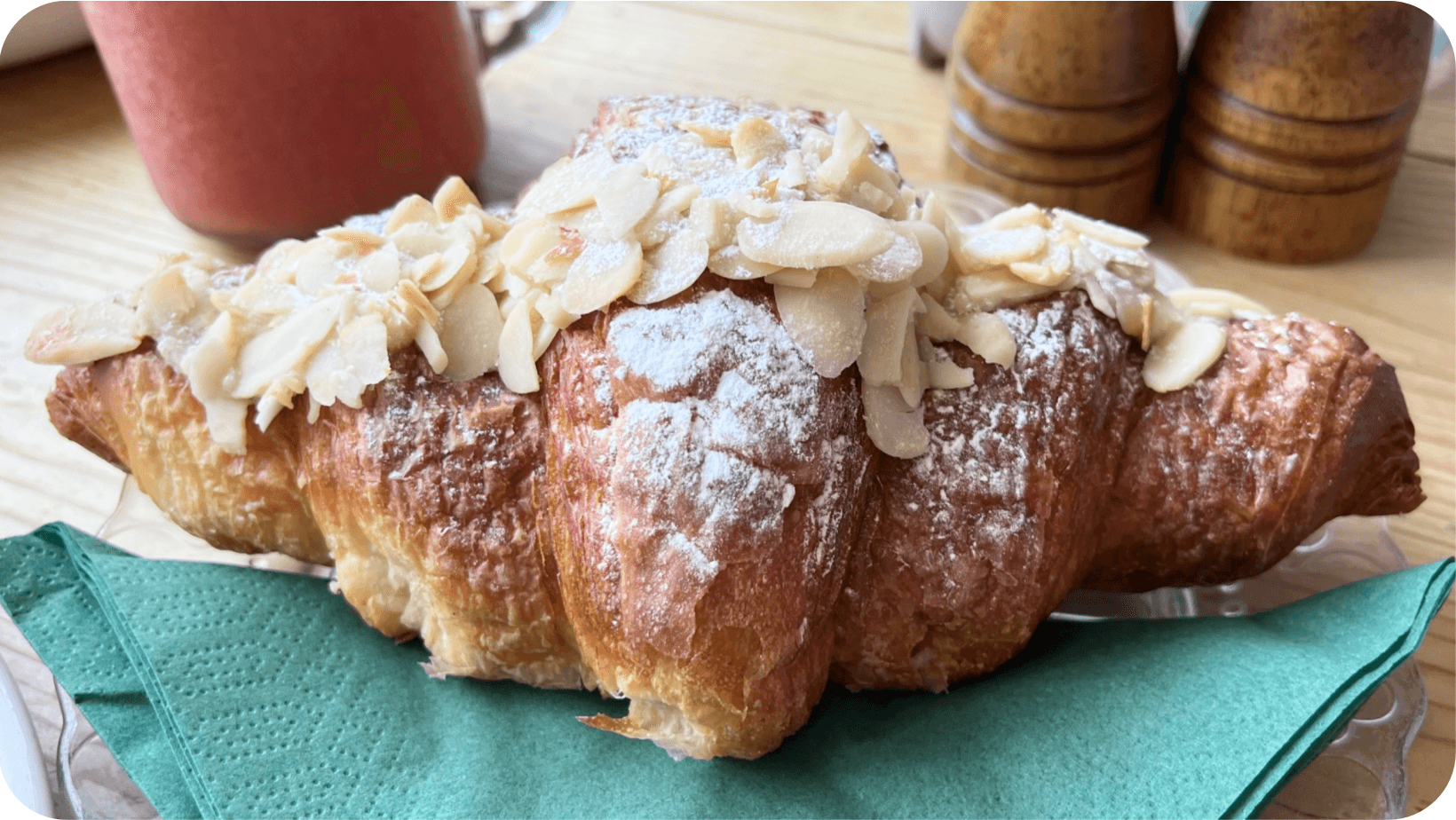 Vegan almond croissant on a blue napkin on a wooden table from Perch & Co in Croxley Green