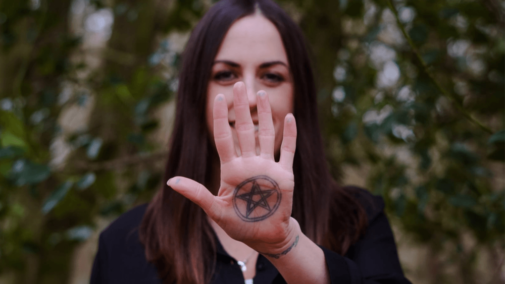 Smiling women with dark hair with her hand outstretched with a star symbol on it