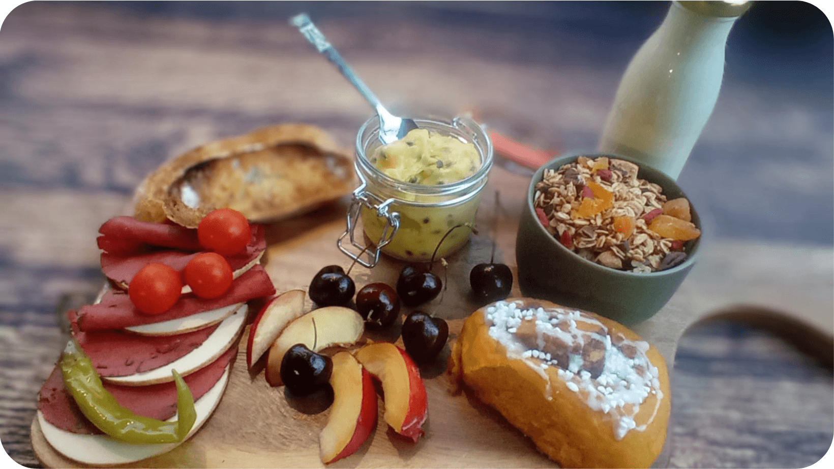 Vegan breakfast from Greenstone Lodge consisting of granola, apple, cherries, tomatoes, brioche and bread on a wooden board