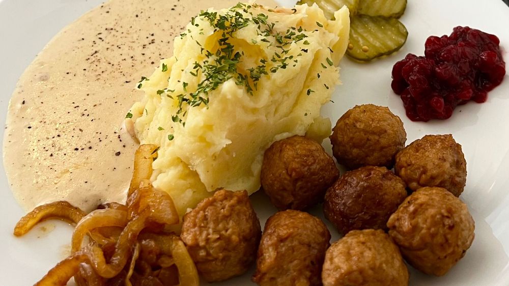 Vegan meatballs with mash, onions, gherkins and red sauce on a white place