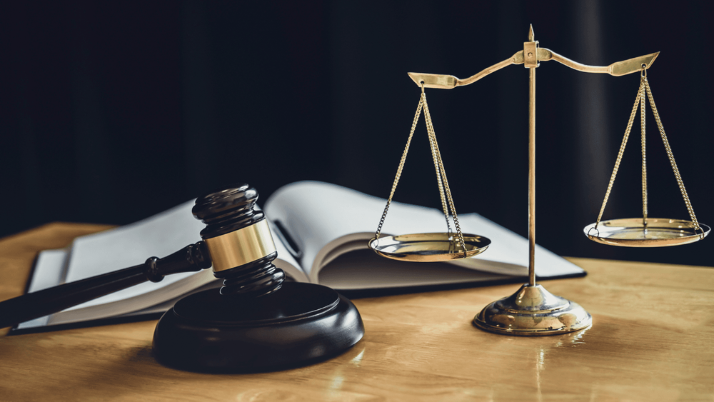 Wooden table with a gavel, gold justice scales and an open book