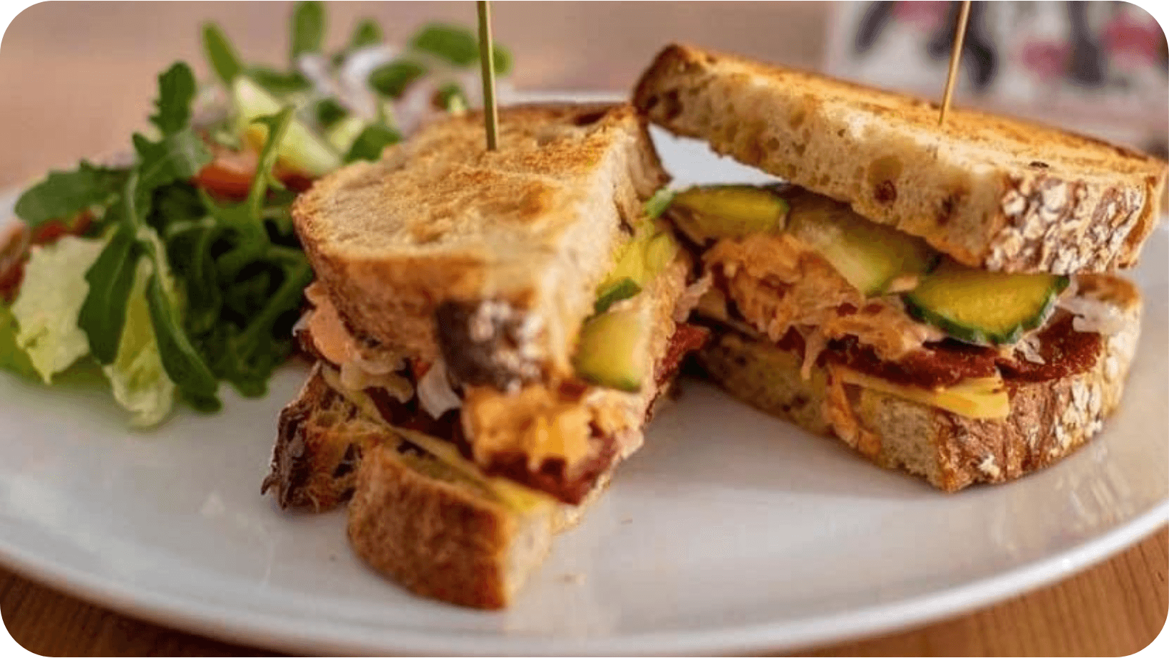 Vegan Reuben sandwich on a white plate with a side of salad in Holy Cow Edinburgh