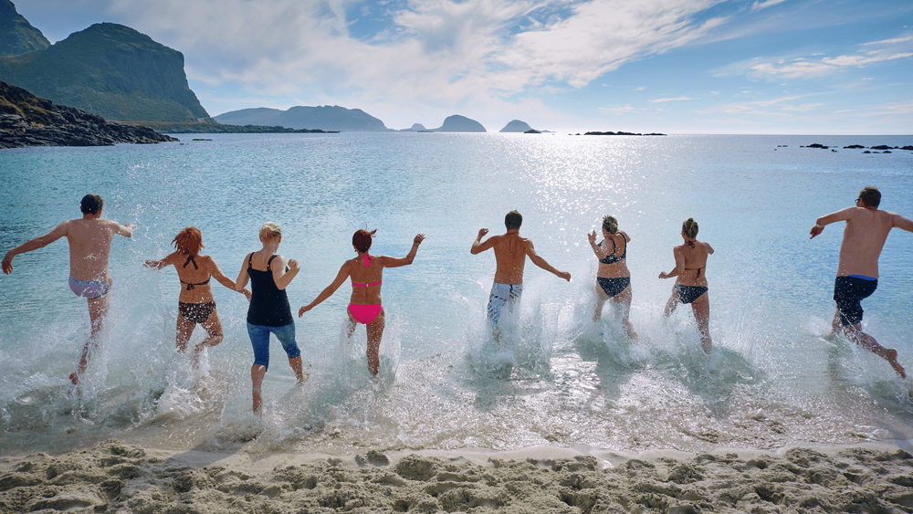  Group of friends running into the sea on a beach