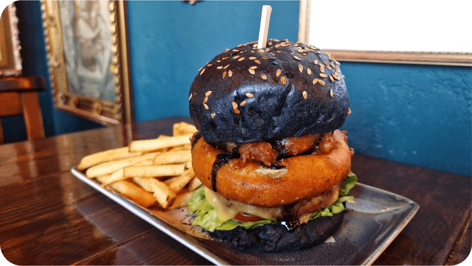 Syko vegan burger with a charcoal bun and chips on a wooden table in Church in Sheffield