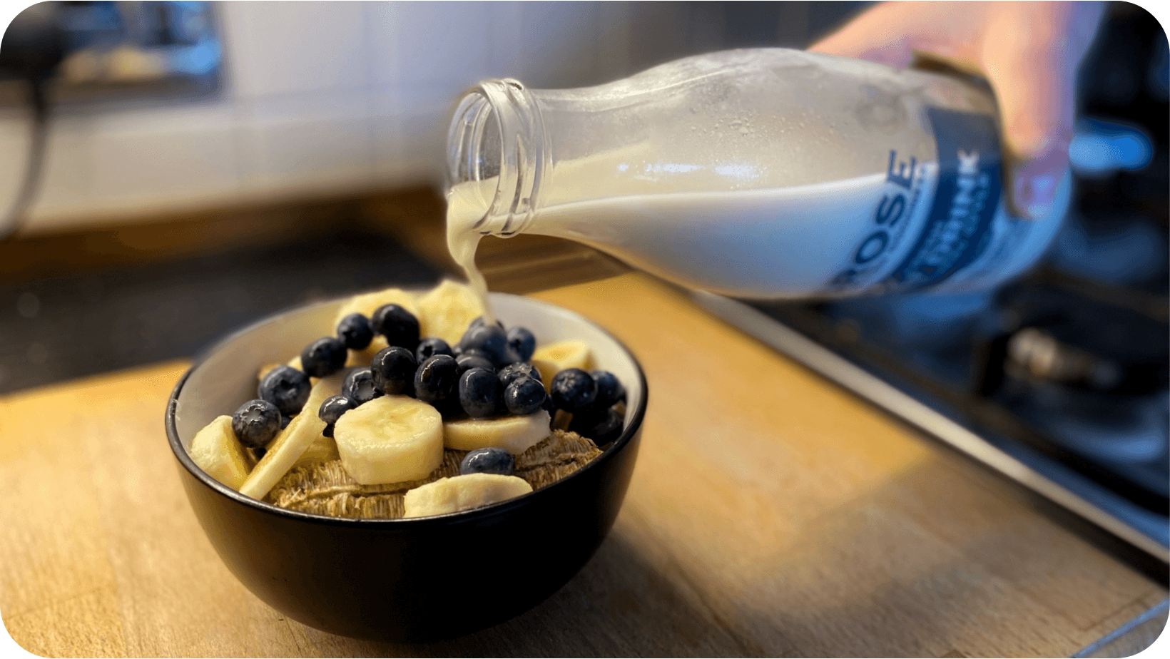 Someone pouring Brose oat drink onto a bowl of cereals and fruit