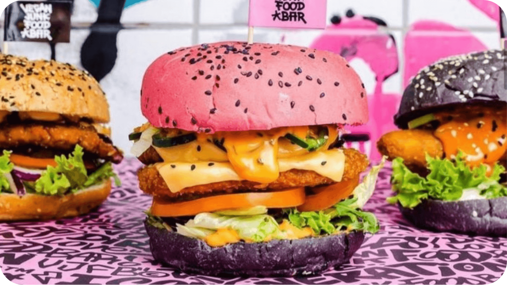 Three multicoloured vegan burgers with a variety of fillings from Vegan Junk Food Bar