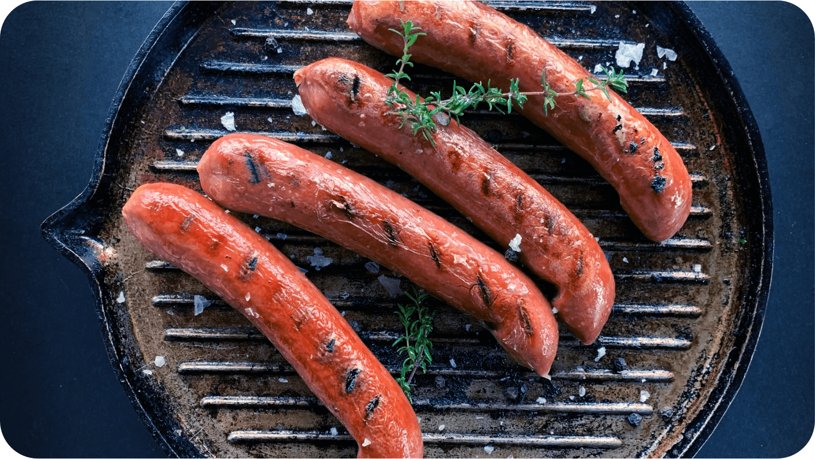 Four grilled vegan sausages on a griddle pan.