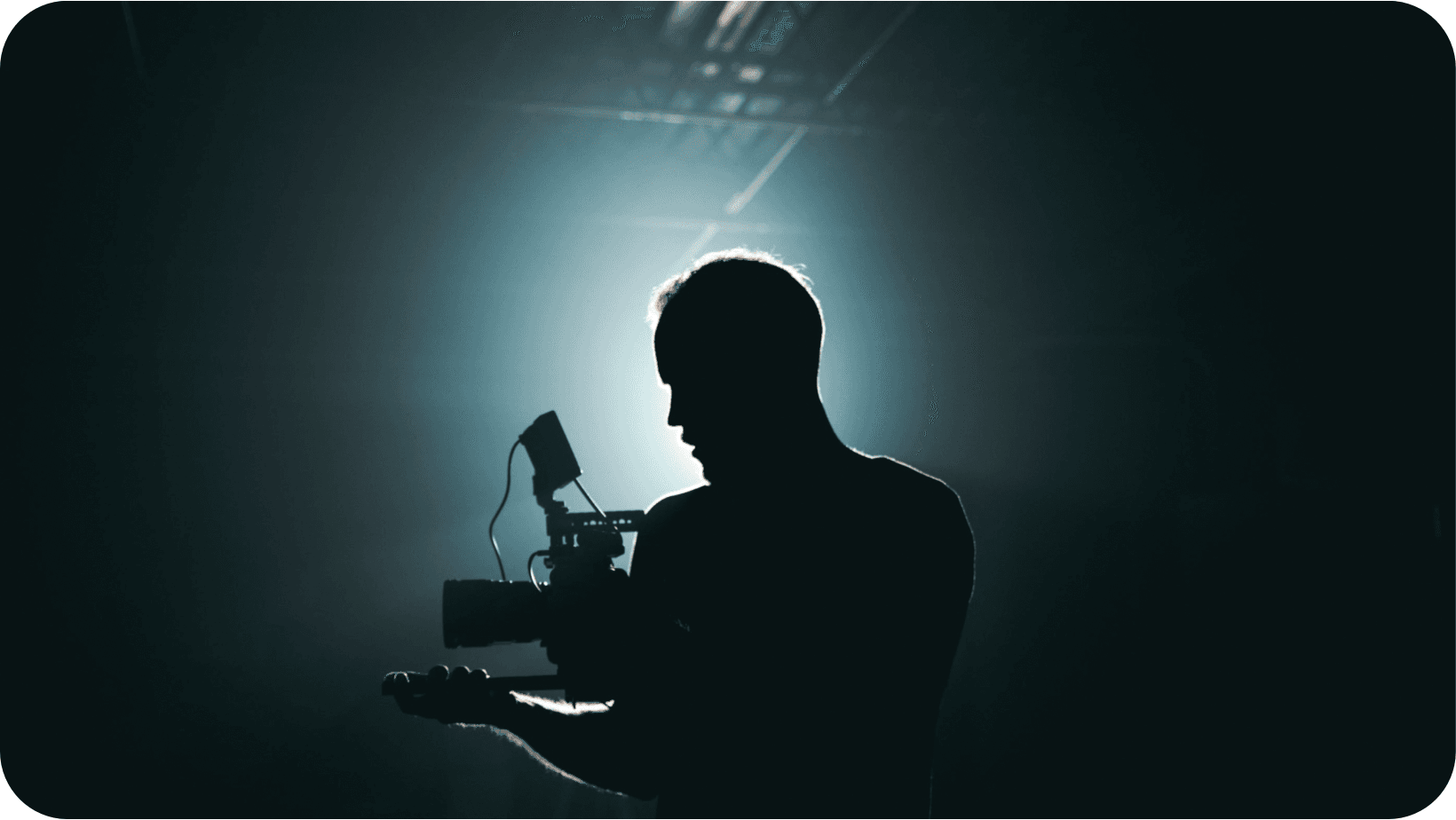 Videographer holding a camera in a dark room