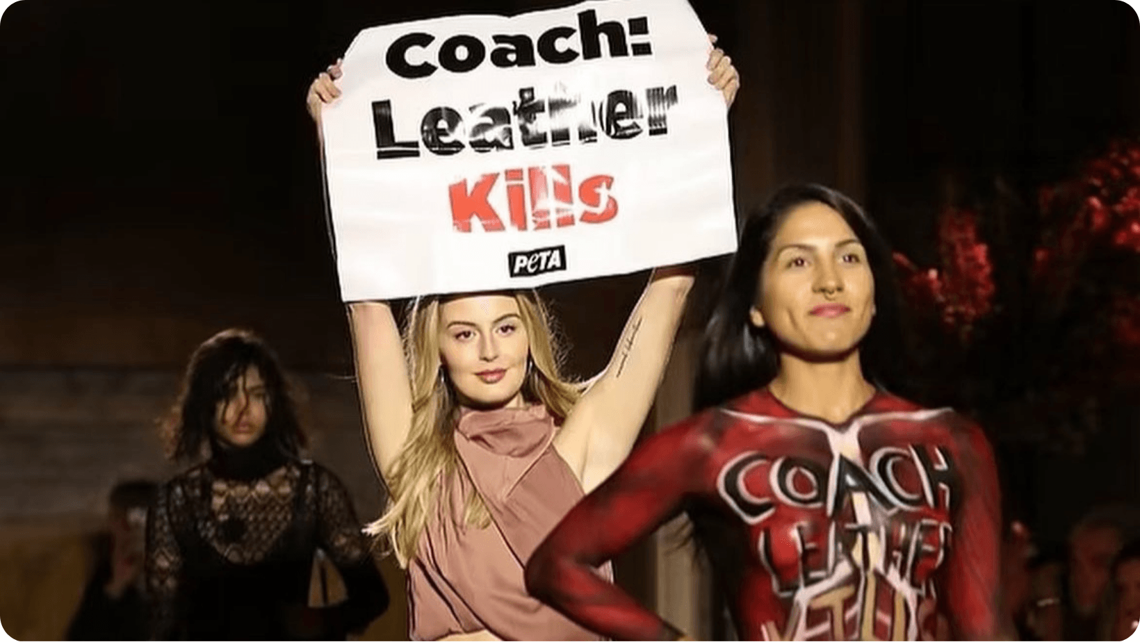 Jamie Logan disrupting Coach’s runway during New York Fashion Week, holding a placard which reads, ‘Coach: Leather Kills’
