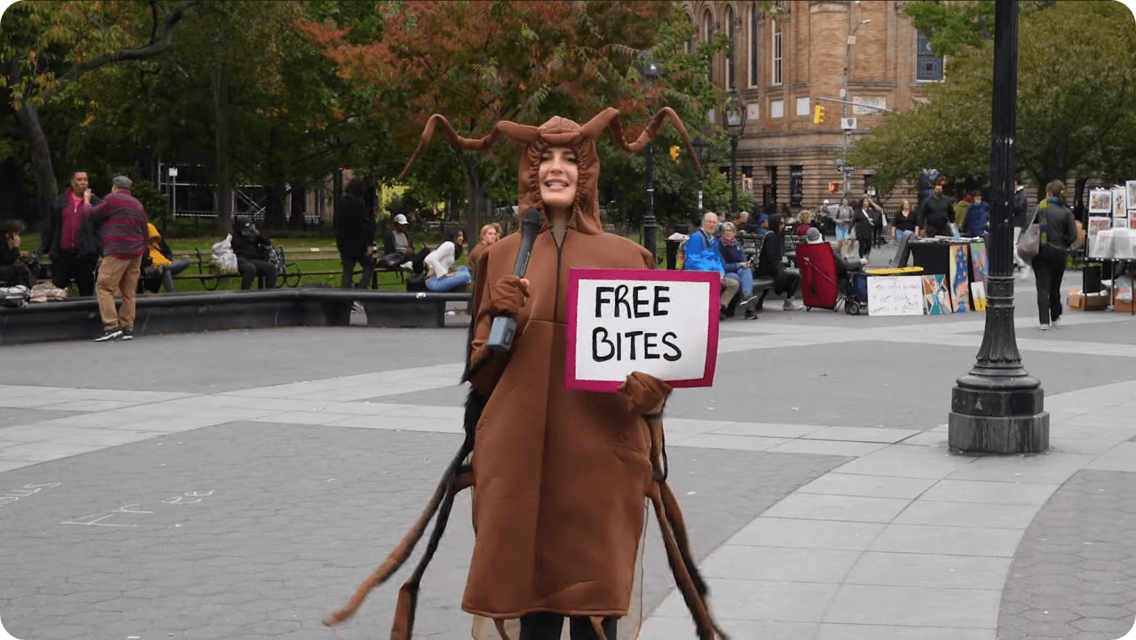 Jamie Logan dressed up as a Lone Star tick in a park holding a sign which says, ‘Free Bites’