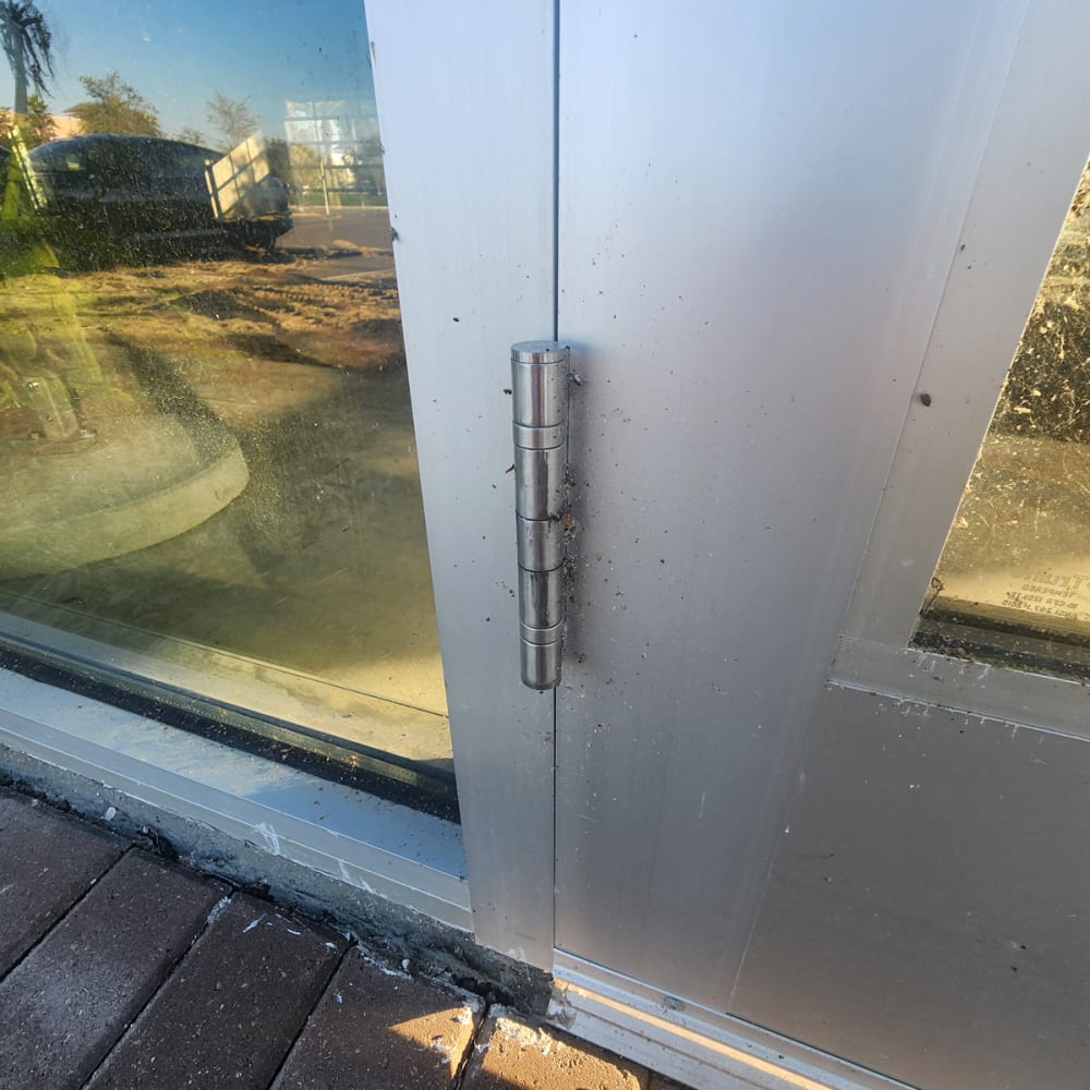 technician adjusting butt hinges on a commercial storefront door in Kissimmee FL