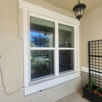Happy Central Florida homeowner looking out through a clear custom window glass pane, representing a 5-star review for Glass Orlando’s custom window glass service.