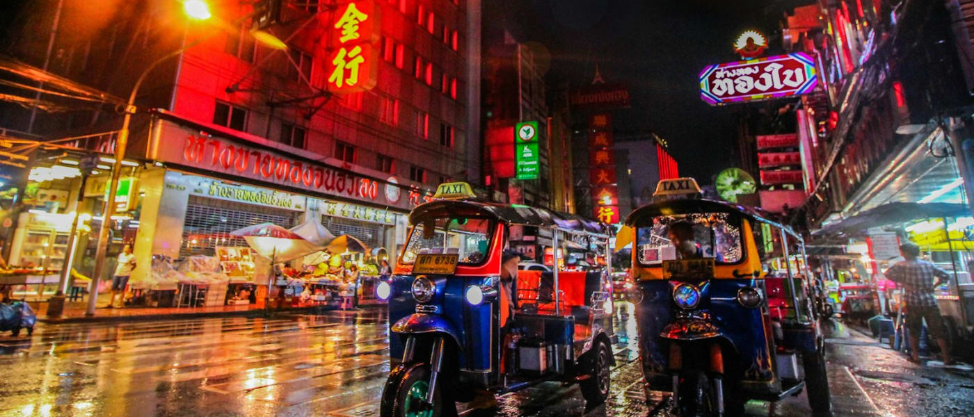 Tuk-tuks in een drukke straat vol neonreclames