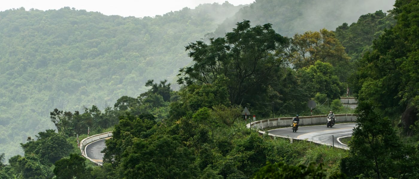 Motorrijders op een kronkelende bergweg door het groen