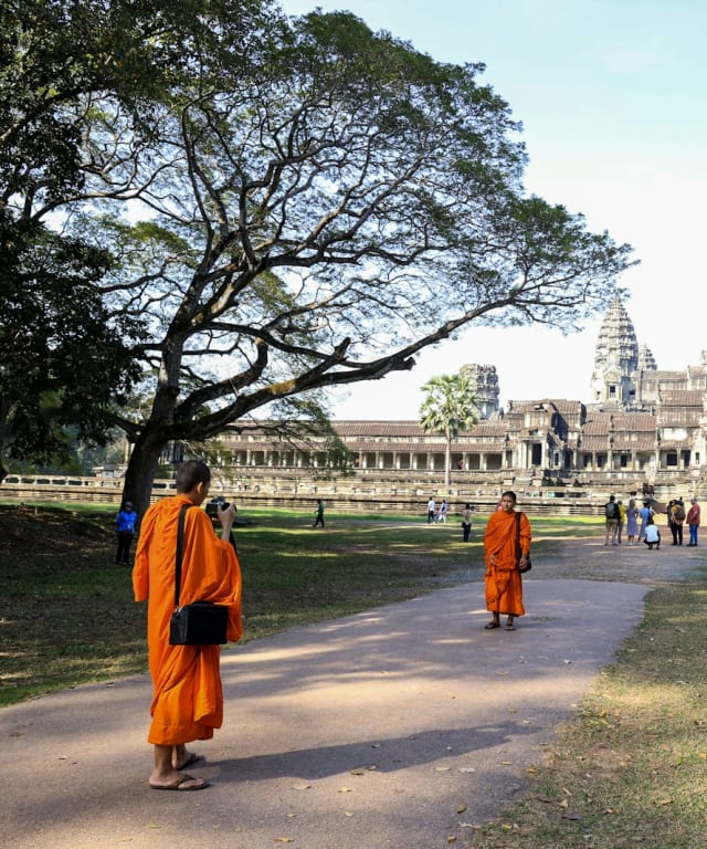 Monniken in oranje gewaden lopen richting Angkor Wat