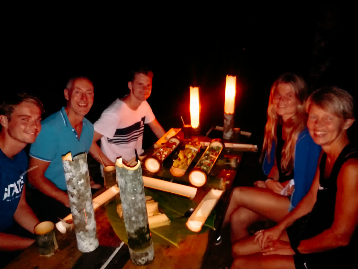 Reizigers aan een tafel bij kaarslicht met het diner uit bamboe