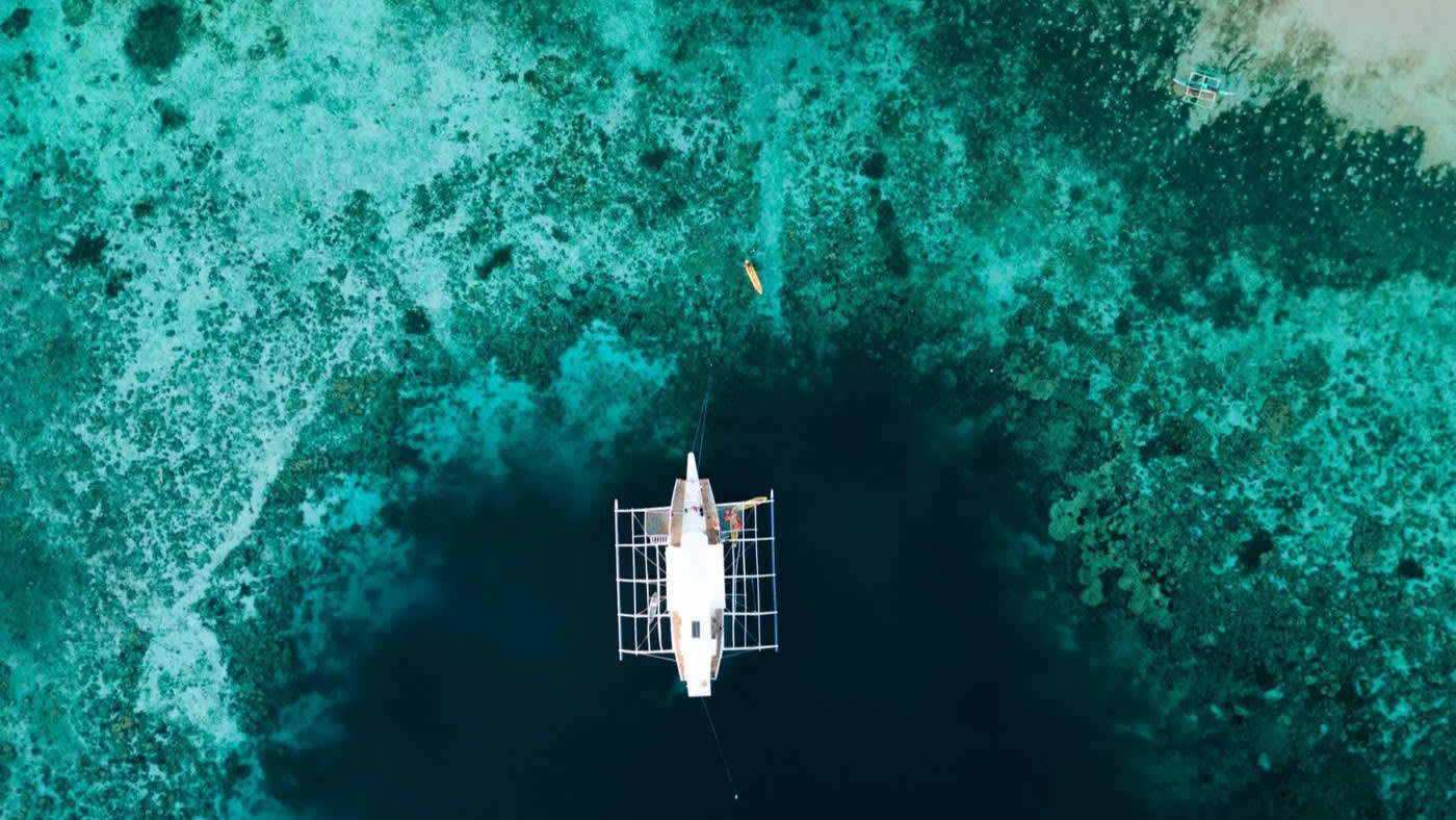 De expeditieboot van bovenaf, boven het koraal van Palawan