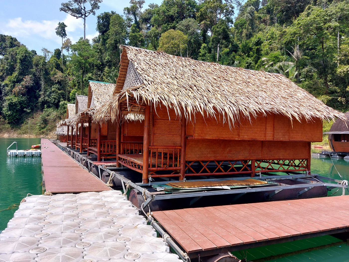 Drijvende rafthouses met rieten daken langs de steiger op Cheow Lan Lake