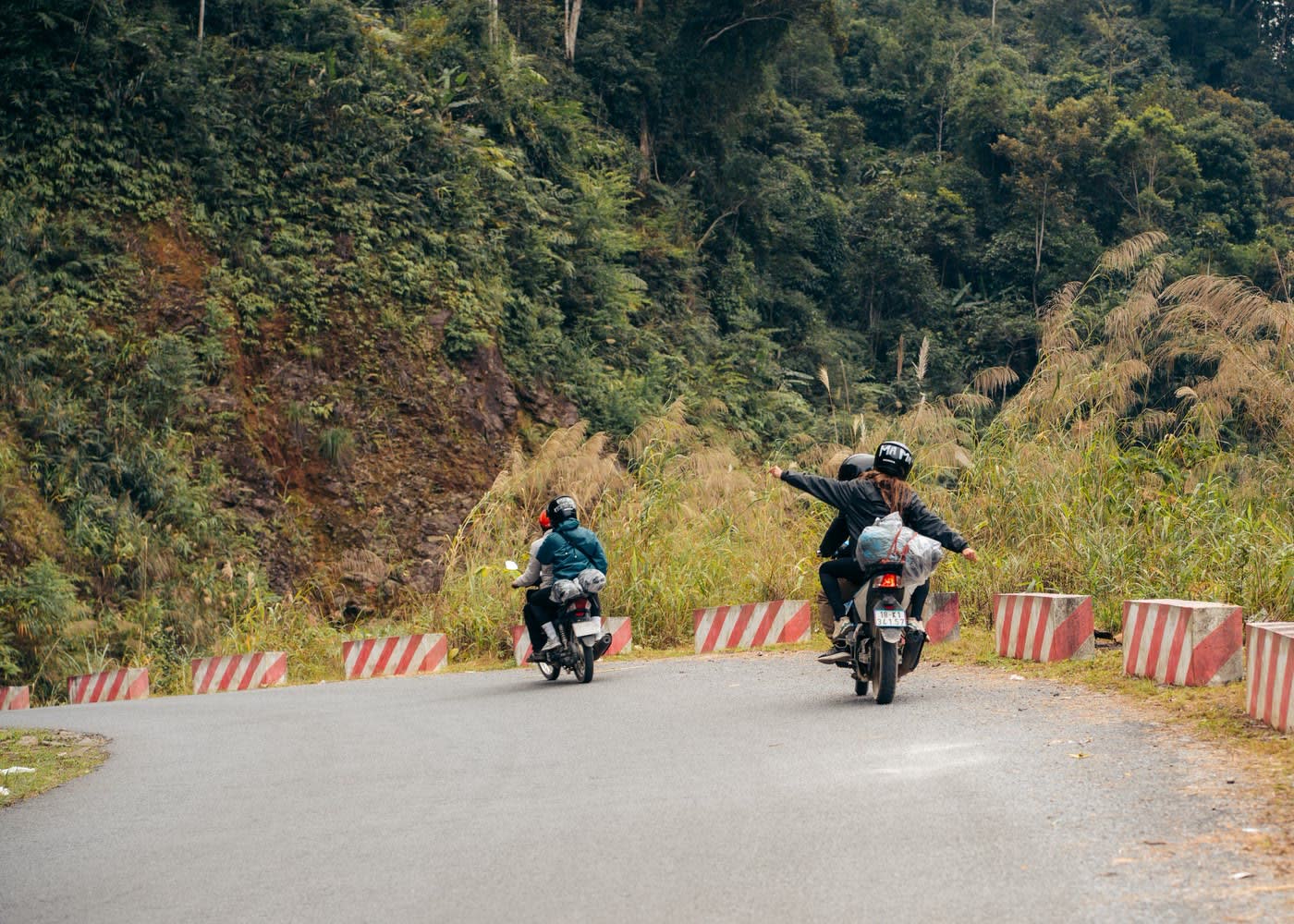Rijders zwaaien onderweg op een bergpas van de Ha Giang Loop