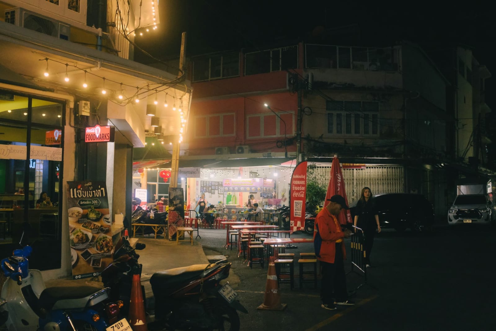 Straat met eetkraampjes en krukjes in de avond in Thailand