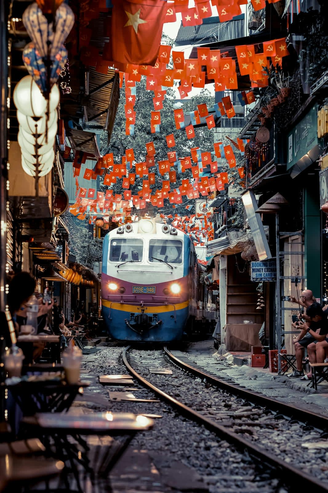 Trein die door de smalle Train Street in Hanoi rijdt, tussen de cafés door