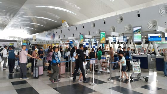 Rij reizigers met bagagekarren bij de incheckbalies van een luchthaven
