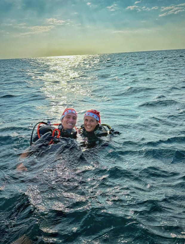 Remco en Anouk in duikuitrusting aan het wateroppervlak bij zonsondergang