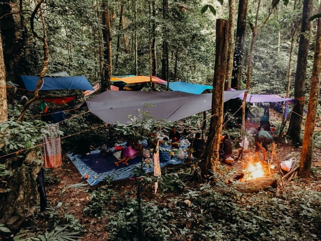 Kamp met hangmatten en tarps rond een kampvuur in het regenwoud van Khao Sok