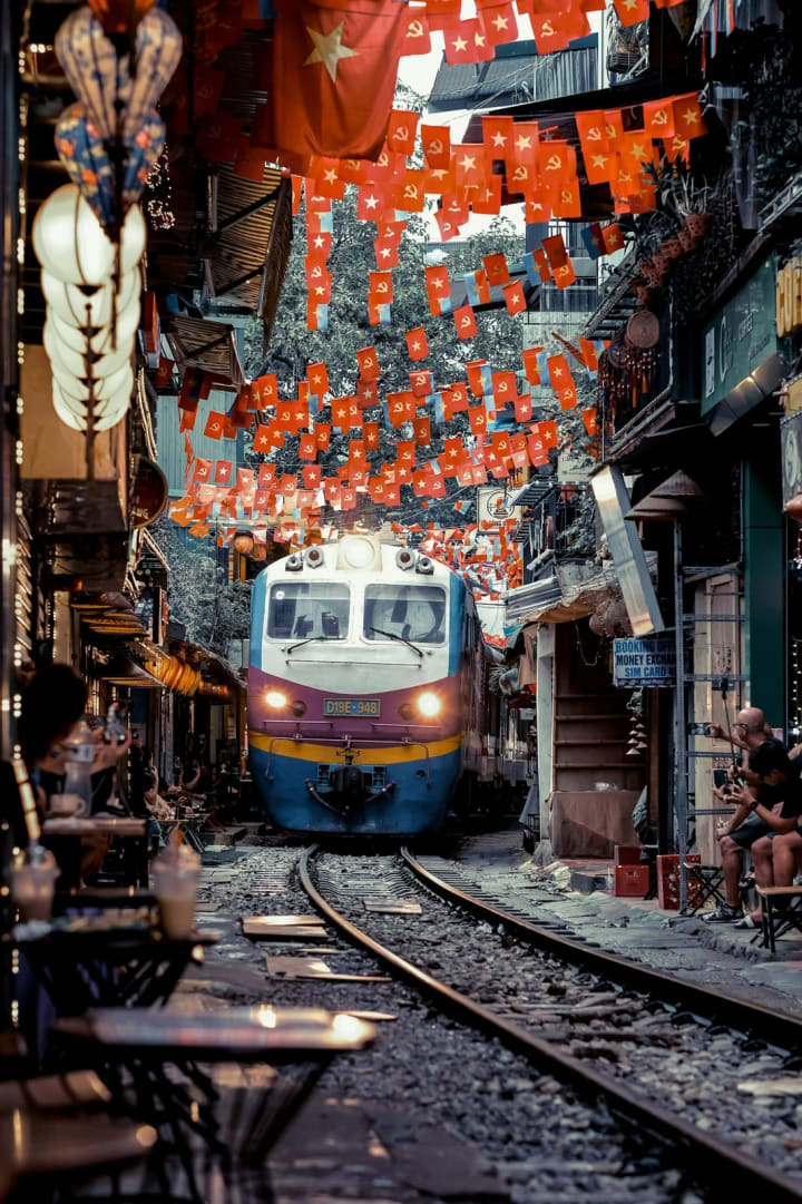 Trein die door de smalle Train Street in Hanoi rijdt, tussen de cafés door
